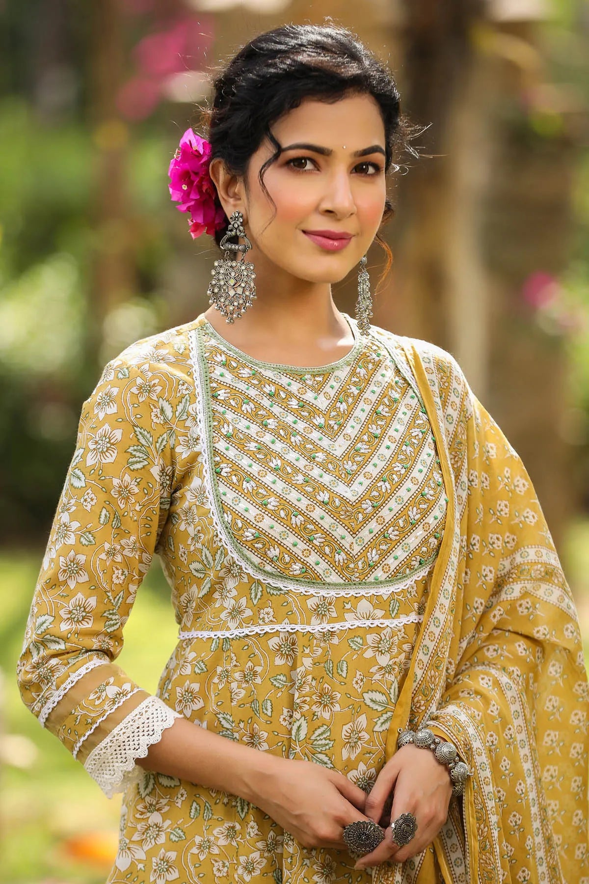 Woman wearing a yellow and white patterned outfit with a floral background
