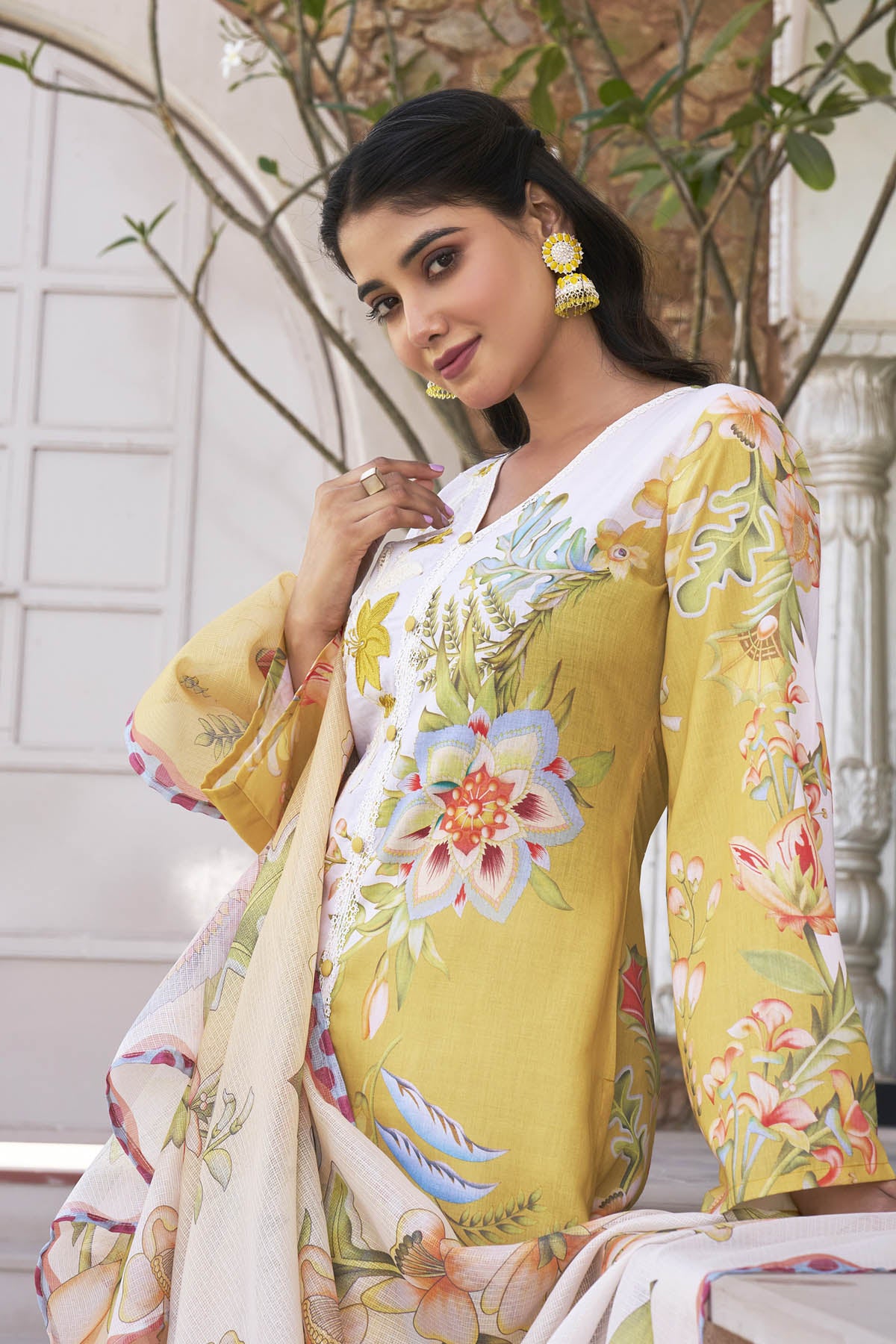 Woman wearing a yellow floral saree with a white blouse in an outdoor setting.