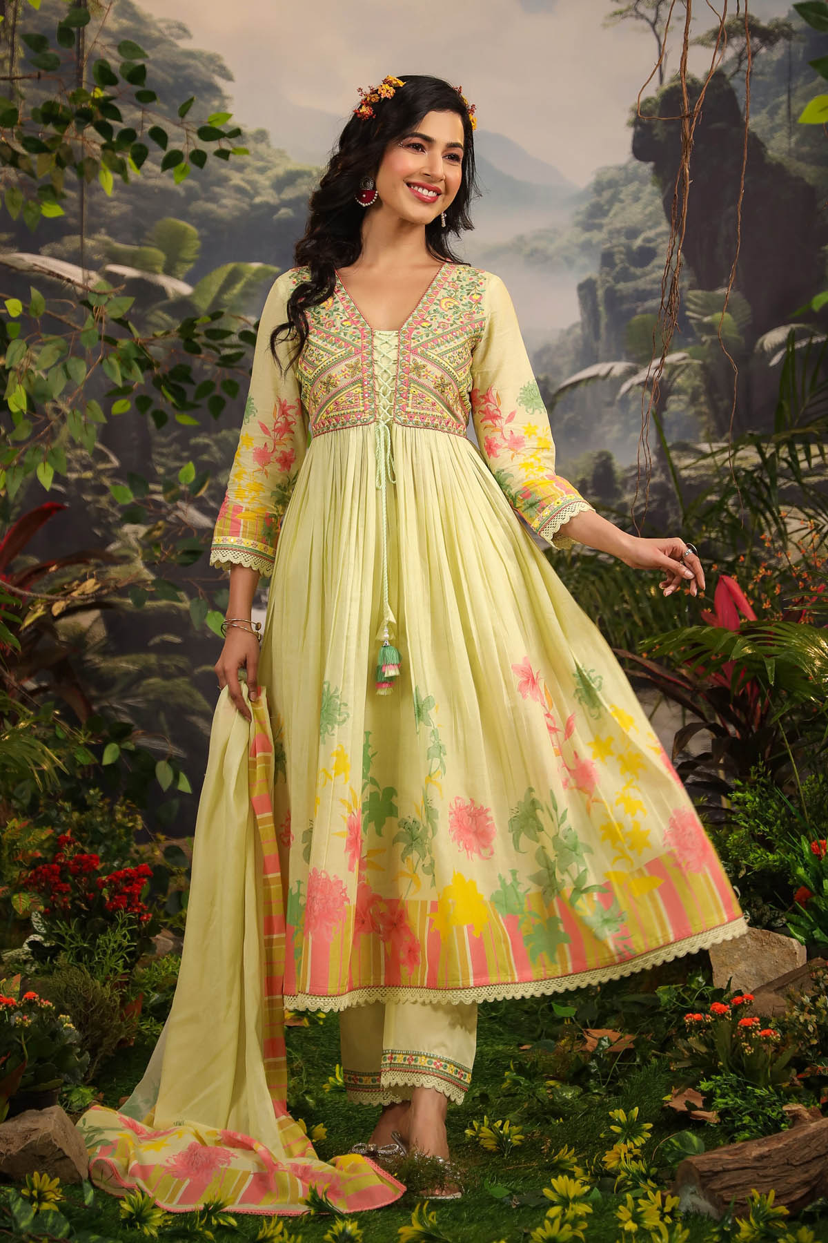 Woman in a light green traditional outfit with floral patterns standing in a natural setting.