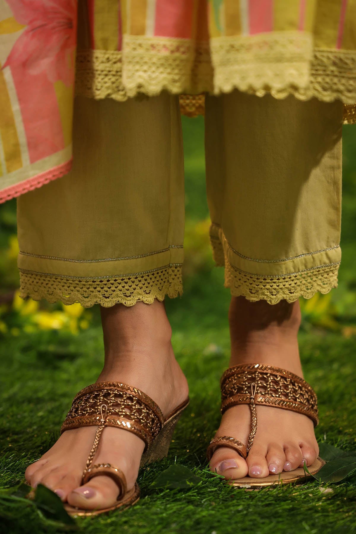 Close-up of feet wearing gold sandals on a grassy background