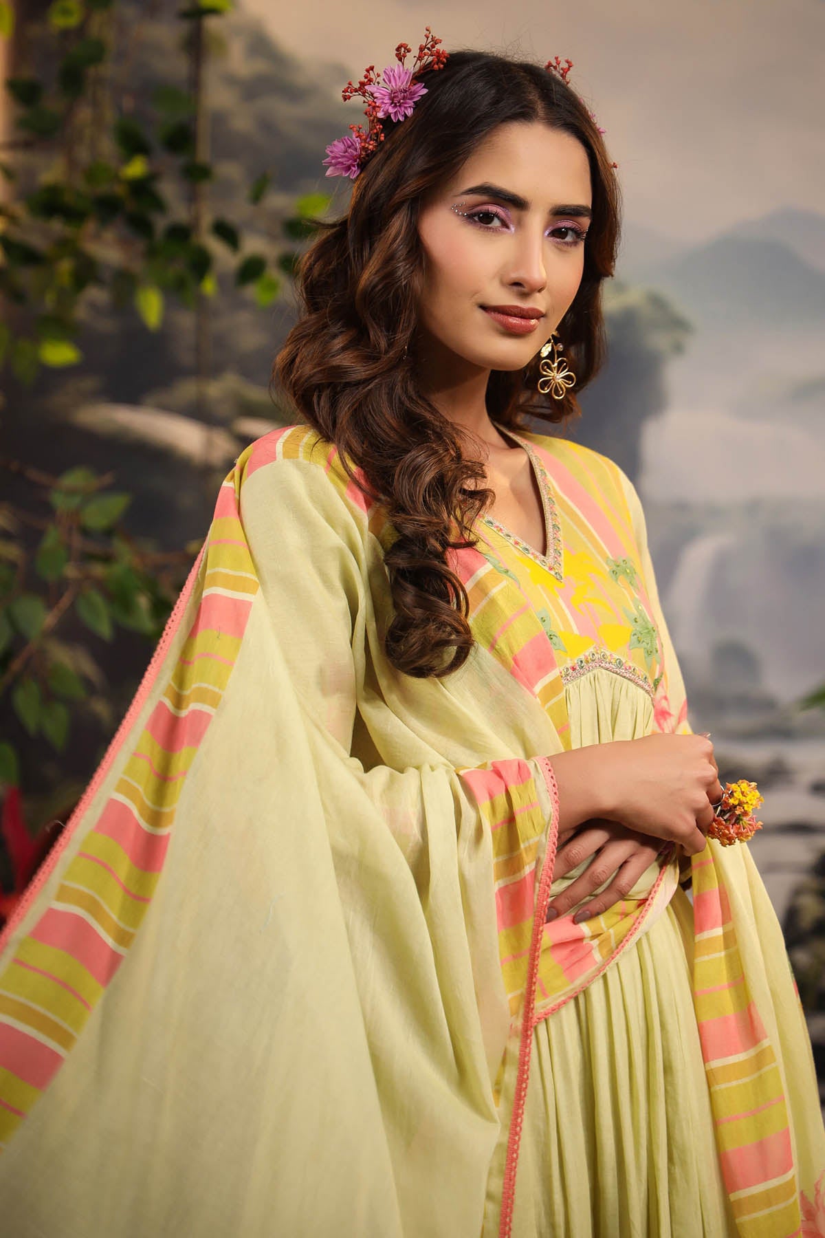 Woman in a light green traditional outfit with pink and yellow accents, standing outdoors.