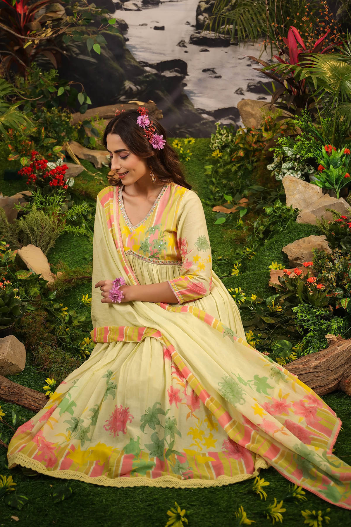 Woman in a floral dress sitting by a stream in a natural setting