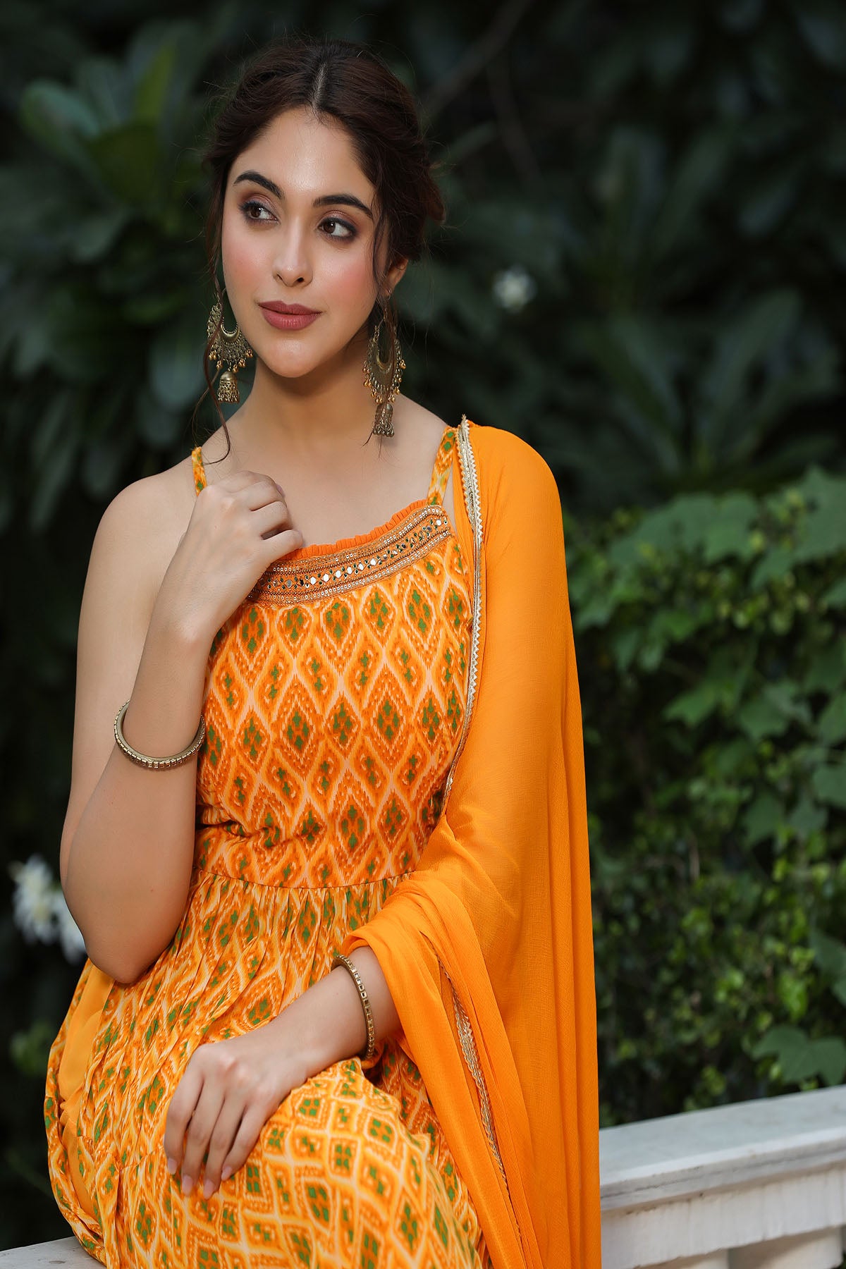 Woman in an orange traditional outfit with a blurred green background