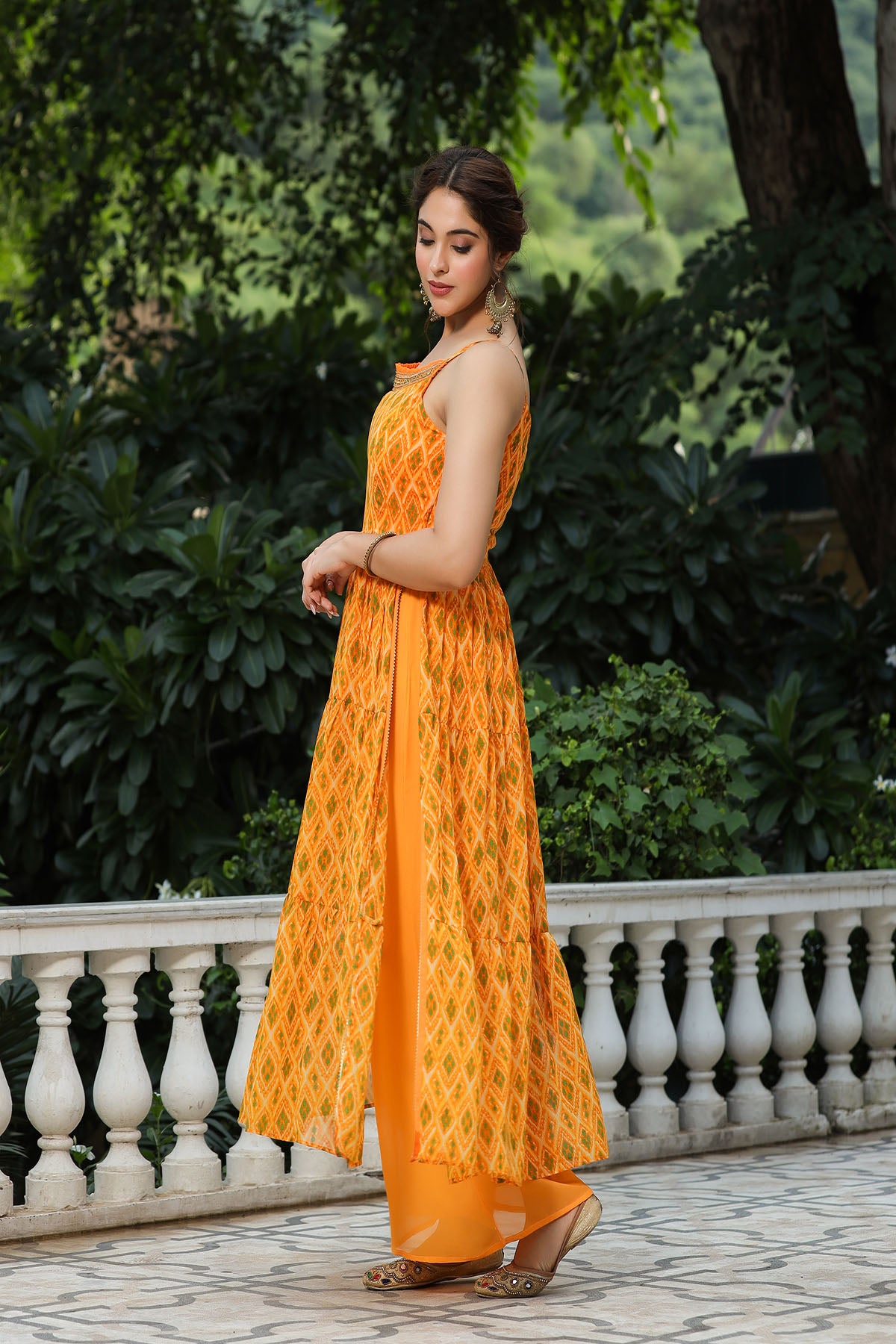 Woman in an orange dress standing outdoors with greenery in the background