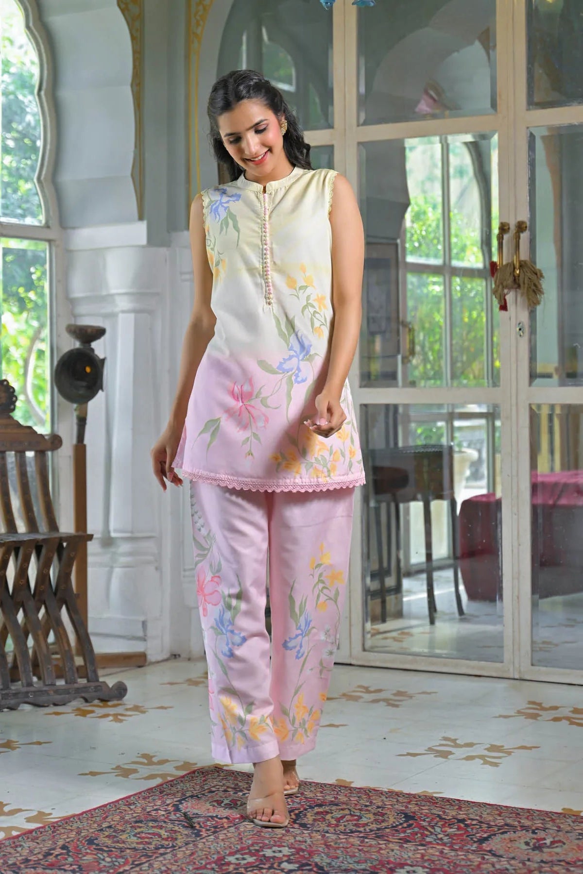 Woman wearing a floral outfit in a decorated room with large windows.