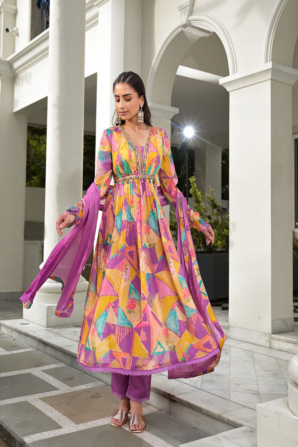 Woman in a colorful dress standing in front of a white building with columns.